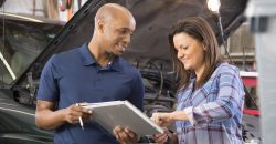 Mechanic explains vehicle repair invoice to customer in auto repair shop